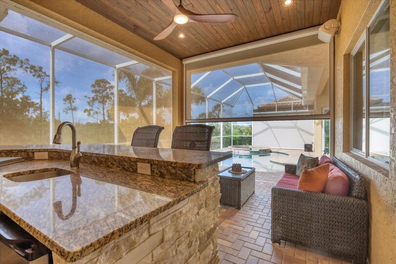 Large outdoor living space overlooking canal and nature preserve. Lanai features ample seating, outdoor kitchen, bar, 65-inch Smart TV, sparkling private pool & spa, and remote controlled privacy screens