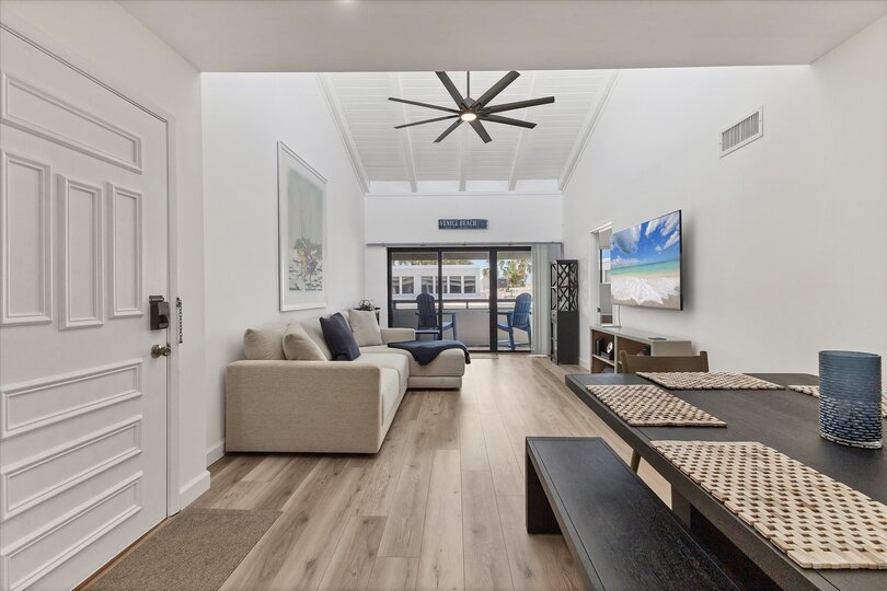 Bright, open living/dining space. Living room features comfy seating, a 65-inch Smart TV and balcony access
